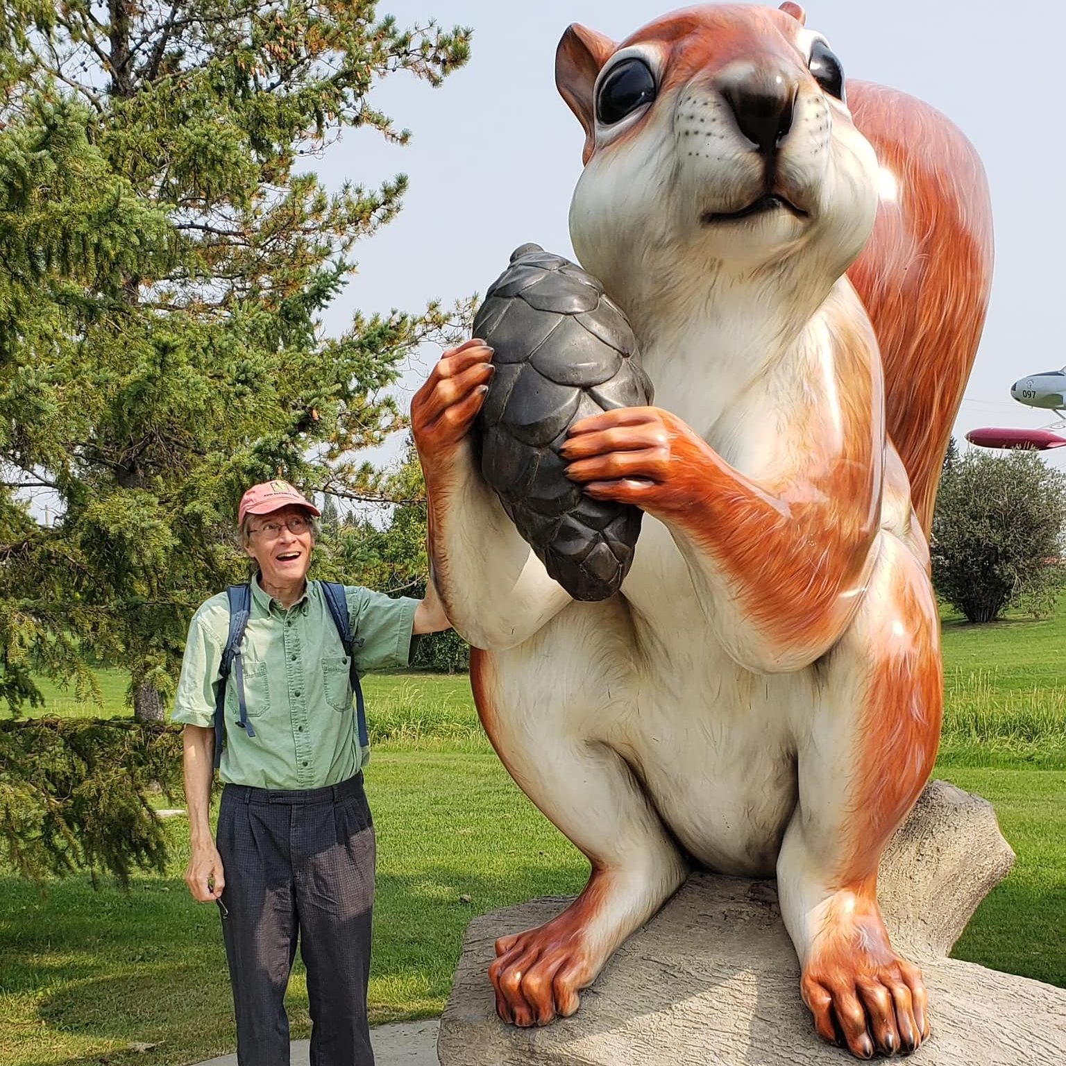 Erik Talvila in front of a gigantic statue of a squirrel holding a pine cone