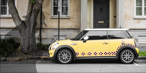 Yellow parked Mini Cooper car with purple polka dots