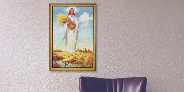 Framed picture of Our Lady of the Prairies hanging above chair