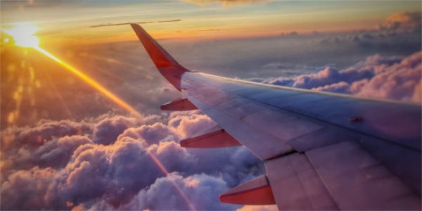 Sun and wing of airplane above clouds