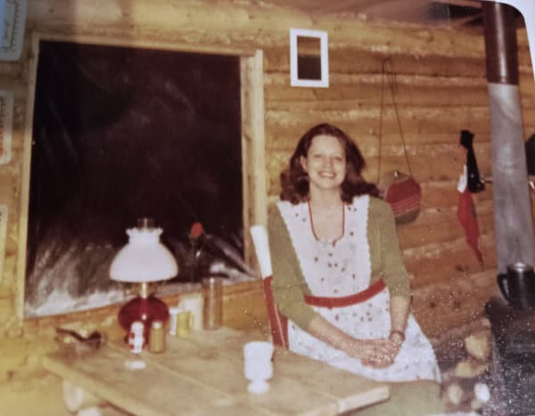 Author sitting at the table in a log cabin.