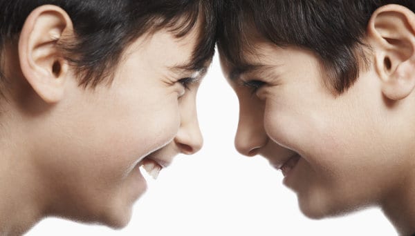 Two laughing boys, looking at each other with their heads touching.