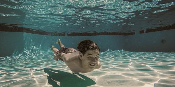 Boy swimming under water in swimming pool.