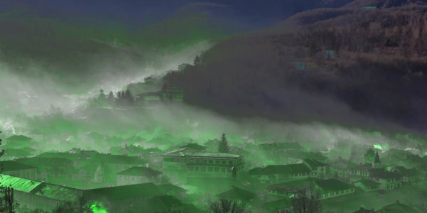 Mountain town surrounded by green fog.