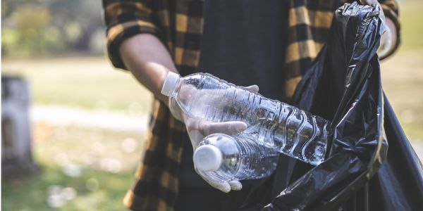 Somebody putting plastic bottles into a plastic bag, in a park