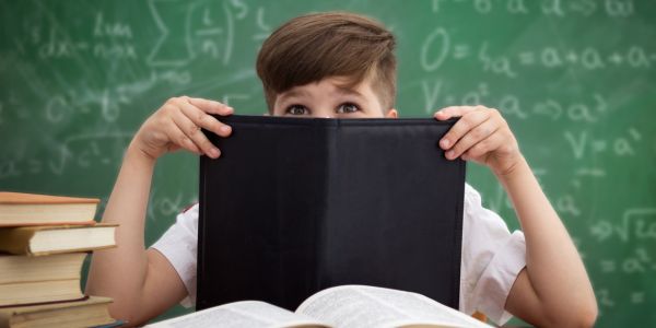 Schoolboy hiding behind a book, embarrased