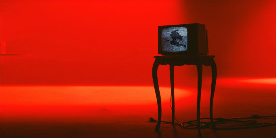 Silhouette of flying witch on television standing on a side table with red background