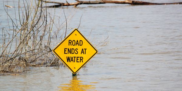 A road sign, its pole entirely immersed in water, saying: "Road Ends At Water". Ah, the irony...