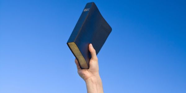 Main holding a Bible in the air