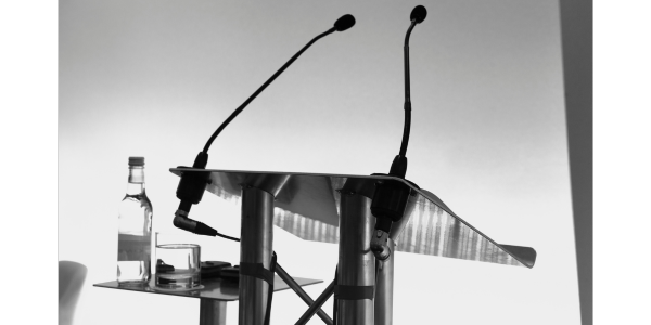 Lectern with microphones and a glass of water.